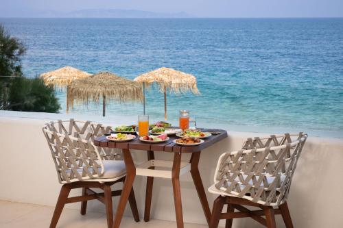 a table with food and drinks on the beach at Isla Brown Corinthia Resort & Spa, Curio Collection by Hilton in Agioi Theodoroi