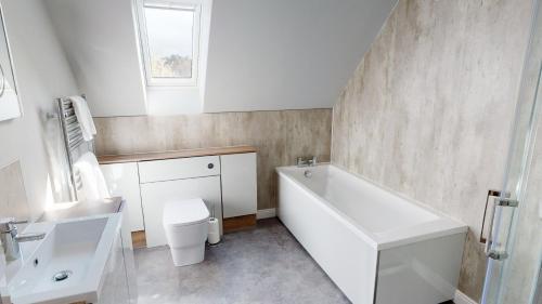a bathroom with a tub and a toilet and a sink at Braeside - Family home in Nethy Bridge in Nethy Bridge