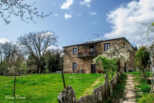 an old stone house with a balcony on a green field at Casa Rural Dana in Castelo