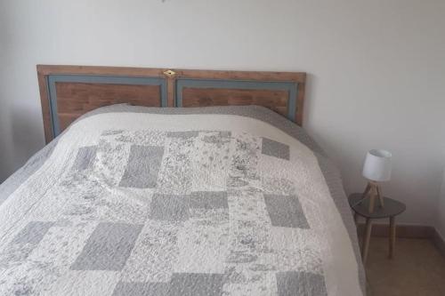 a bed with a gray and white quilt on it at Le petite maison du Crembreux in Marquise