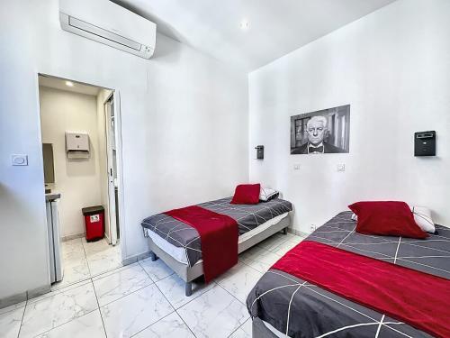 2 Betten in einem Zimmer mit weißen Wänden und roter Bettwäsche in der Unterkunft Sweet Home Marceau 6 studios hyper centre proche de la mer et du palais in Cannes