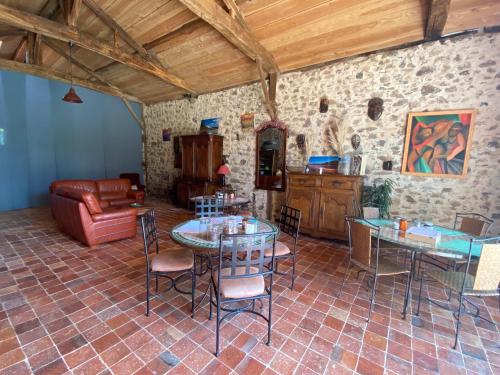 een woonkamer met tafels en stoelen en een bank bij La Frapperie in La Pommeraie-sur-Sèvre