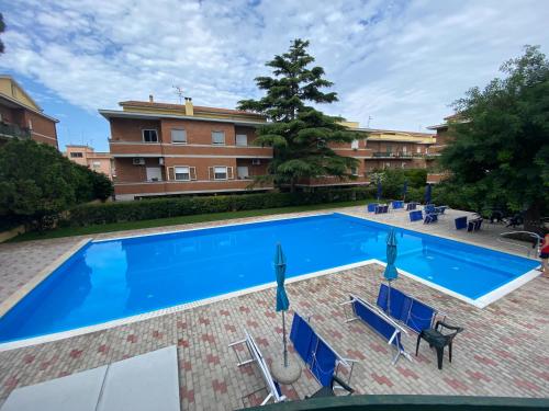 une grande piscine avec des chaises bleues et un bâtiment dans l'établissement Simply House Civitavecchia, à Civitavecchia