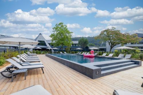 a swimming pool with lounge chairs and a pink float at Miura in Voglans