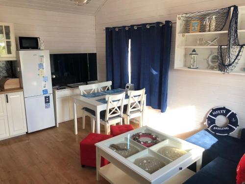 a living room with a table and a kitchen with a refrigerator at Dom Wakacyjny Baltic Home & Dom Baltic Home Garden Inn in Zastań