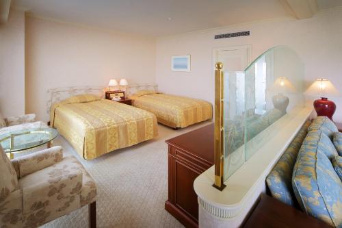 a hotel room with two beds and a couch at Hotel Springs Makuhari in Chiba