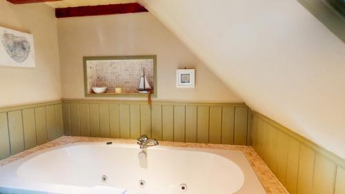 a bathroom with a bath tub in the attic at The Maltings - lodge with hot tub in Nethy Bridge