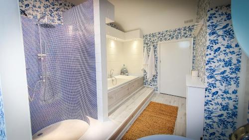a bathroom with a tub and a shower with blue and white wallpaper at Rose House in Glenarm