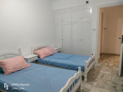 two beds in a small room with blue and pink pillows at North coast in El Alamein