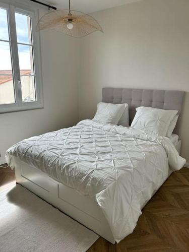 un lit blanc dans une chambre blanche avec une fenêtre dans l'établissement Maison de Ville Cannes Centre, à Cannes