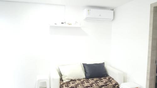 Habitación blanca con sofá y almohadas blancas y negras en Departamento en Tonsupa en Tonsupa
