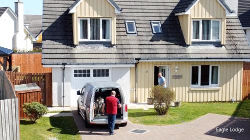 a man opening the door of a van in front of a house at Eagle Lodge - Aviemore Lodges in Aviemore