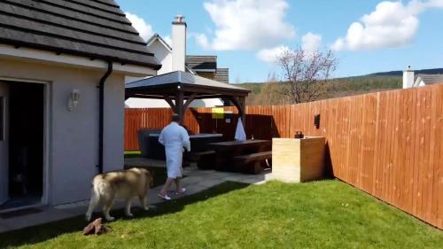 a man and a dog standing in a backyard with at Eagle Lodge - Aviemore Lodges in Aviemore