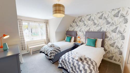a bedroom with two beds and a window at Eagle Lodge - Aviemore Lodges in Aviemore