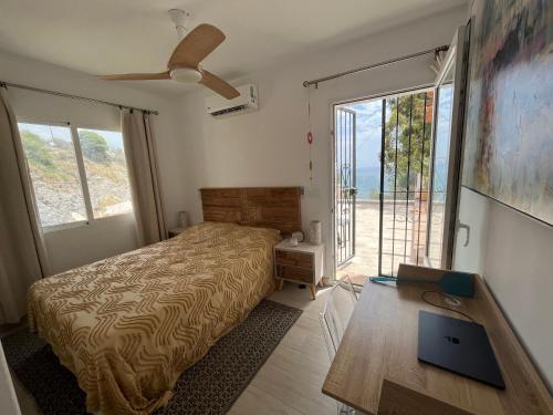 a bedroom with a bed and a desk with a laptop at El Nido in Mojácar