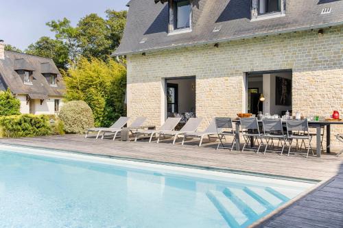 een patio met een tafel en stoelen naast een zwembad bij Villa Azif - Superbe Maison avec Piscine - St Pierre Azif in Saint-Pierre-Azif