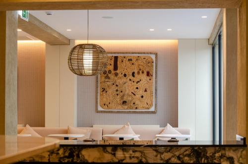 a dining room with white tables and a painting on the wall at OMID Saldanha Hotel in Lisbon