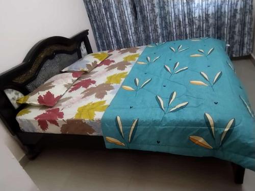 Una cama con una cubierta azul con hojas. en P. G. REDDY HOME STAY en Tirupati