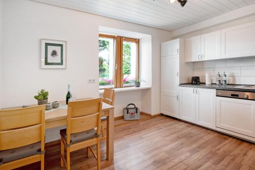 a kitchen with white cabinets and a wooden table at Haus Bergruh Fuchsbau in Todtnauberg