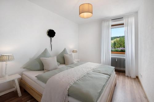 ein weißes Schlafzimmer mit einem Bett und einem Fenster in der Unterkunft Haus Bergruh Fuchsbau in Todtnauberg