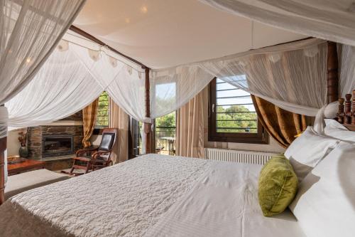 a bedroom with a large white bed with curtains at Oreiades Guesthouse in Parthenón