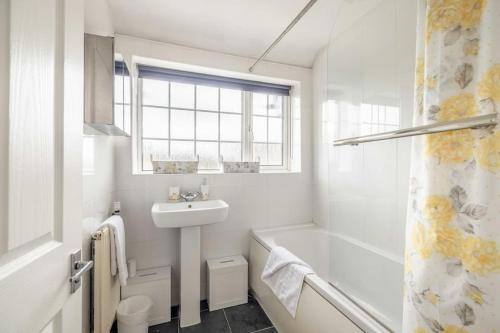 uma casa de banho branca com um lavatório e uma banheira em 3-Bed Family Home with Parking & Large Garden em Windsor
