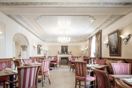 a restaurant with tables and chairs and a chandelier at Hotel Donauhof in Deggendorf