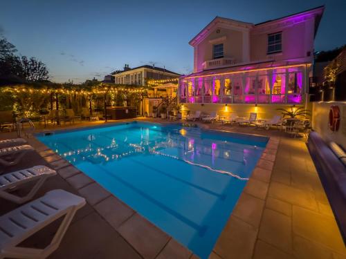 a swimming pool in front of a building at night at Riviera Lodge Hotel in Torquay