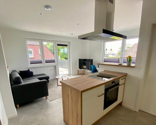 a kitchen and living room with a couch and a stove at Ferienwohnung Strandkorb - Haus Seeschwalbe in Wangerland