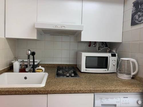 a kitchen counter with a microwave and a sink at Encanto Casa com Spa Jacuzzi Open Space in Tinalhas