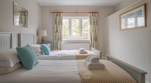 a bedroom with two beds and a window at Keepers Cottage in Rusland