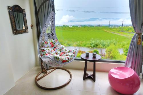 a hammock sitting in front of a window with a table at Flower B & B in Dongshan