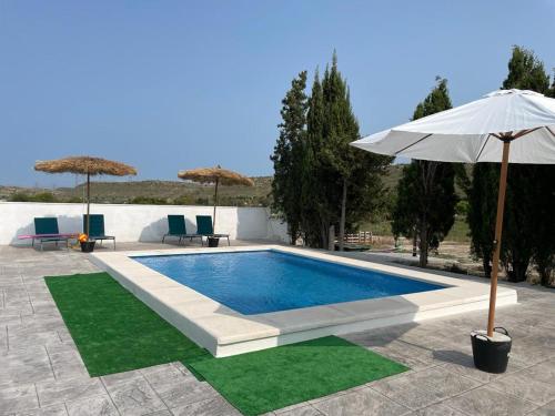 - une piscine avec un parasol, des chaises et des tables dans l'établissement Villa a 10 km de Alicante y playas, à Elche