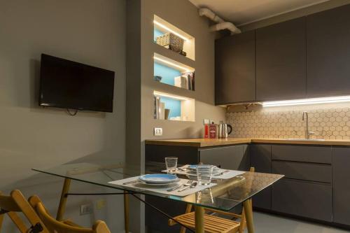 a kitchen with a glass table with chairs and a tv at Appartamento - Ticinese77 in Milan