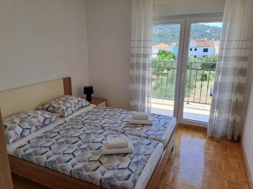 a bedroom with a bed and a large window at Apartments Neli in Vinišće