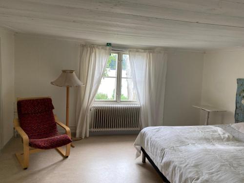 ein Schlafzimmer mit einem Bett, einem Stuhl und einem Fenster in der Unterkunft Gåvetorps Gård in Alvesta