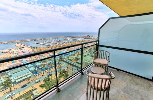 een balkon met 2 stoelen en uitzicht op het strand bij Leonardo Hotel Fuengirola Costa del Sol in Fuengirola