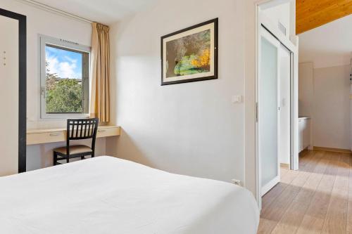 a bedroom with a bed and a chair and a window at Résidence Cala Sultana Appartement T2 in Porto-Vecchio