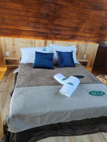 uma cama com almofadas azuis e brancas em CABANAS CHEIRO DE MATO em Cambará