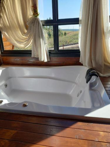 uma banheira branca num quarto com uma janela em CABANAS CHEIRO DE MATO em Cambará