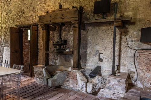 a living room with a stone wall with a tv at Frantoio Del Moscatello in Camaiore