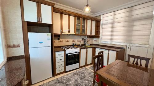 a kitchen with a white refrigerator and a table at Heaven Meydan Apartments in Trabzon
