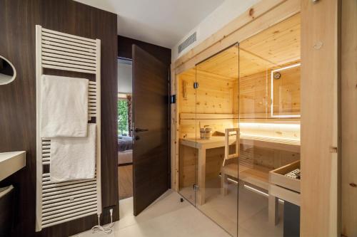 uma casa de banho com paredes de madeira e uma porta de vidro em Schenna Chalet - Apt Stefan em Scena