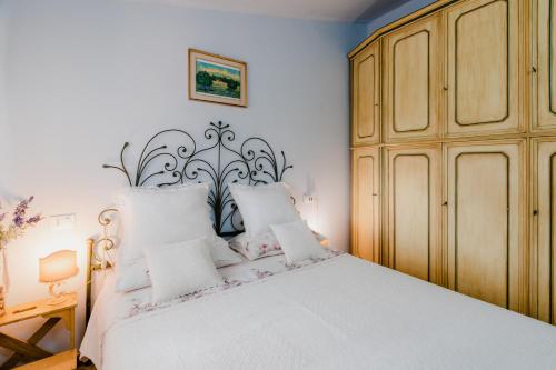 una camera da letto con un grande letto bianco con cuscini bianchi di la tana del geco a Massarosa