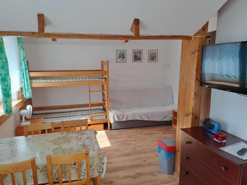 a room with a dining table and a television and bunk beds at Willa Słoneczna - Magdalena i Michał Żelewscy in Karwieńskie Błoto Pierwsze