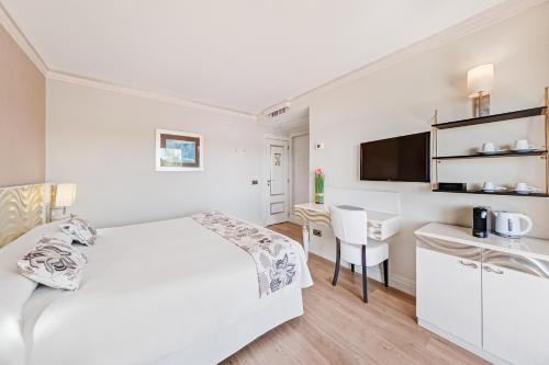 a white bedroom with a bed and a desk at Boutiquehotel El Coto in Colonia Sant Jordi