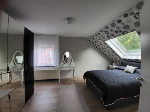 Schlafzimmer mit einem Bett, einem Fenster und einem Spiegel in der Unterkunft Ferienhaus La Farfalla in Munster im Heidekreis