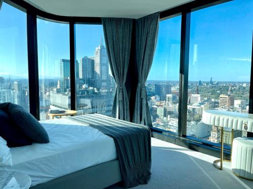 a bedroom with a bed and large glass windows at Sweet Home Apartment Melbourne CBD in Melbourne