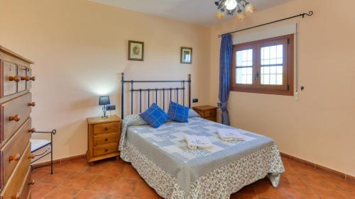 Alozaina的住宿－Casa Huerta Alejo Alozaina by Ruralidays，一间卧室配有一张带蓝色枕头的床和一扇窗户。