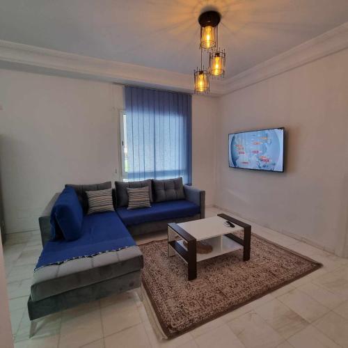 a living room with a blue couch and a table at City View, Ennasr Spacious s2 Apartment in Ariana